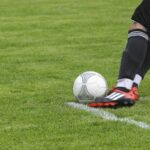 Dynamic shot of a soccer player kicking the ball on a grassy field, showcasing fast-paced sports action.