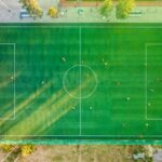 Aerial shot of a soccer game with players on a vibrant green field.